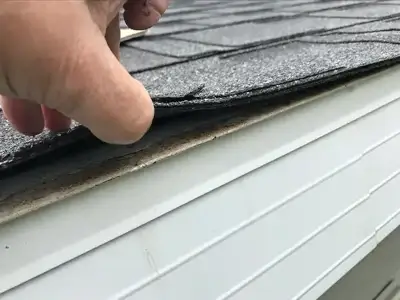 Close up of a worker inspecting underneath a residential roof shingle